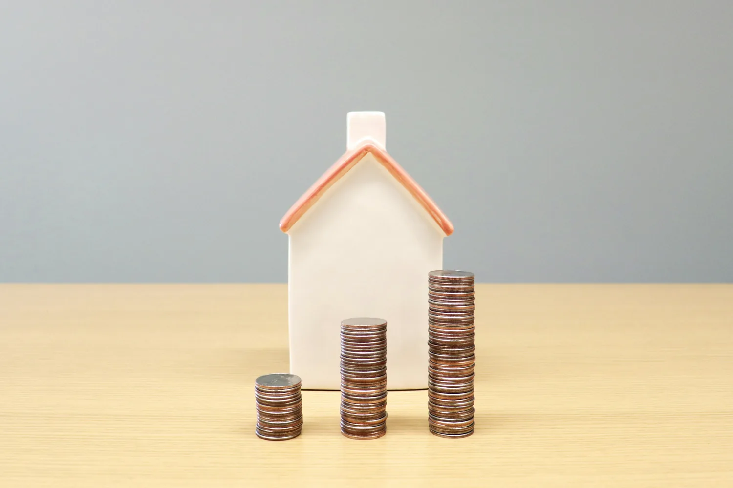Model home and coins representing mortgage cost comparisons